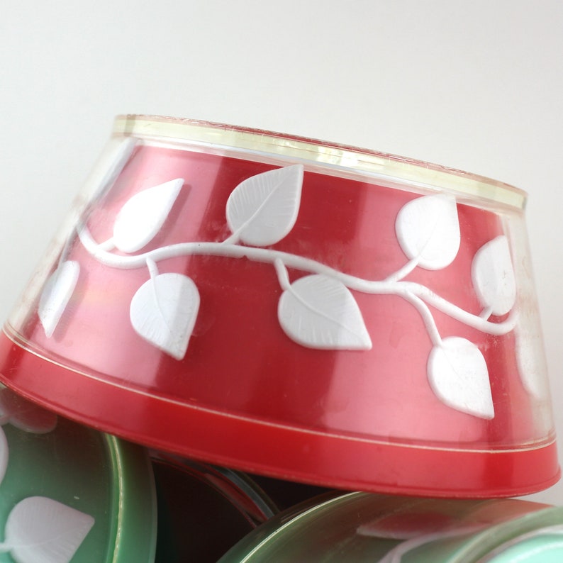 May include: A set of red plastic bowls with white leaf designs. The bowls are stacked on top of each other.