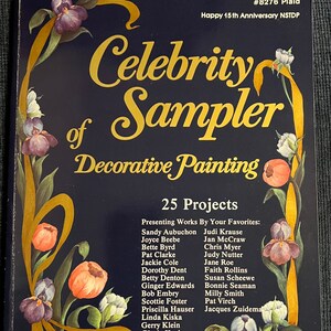 May include: A book cover for "Celebrity Sampler of Decorative Painting" with gold lettering and floral illustrations on a navy blue background. The cover includes the text "25 Projects" and a list of contributors.