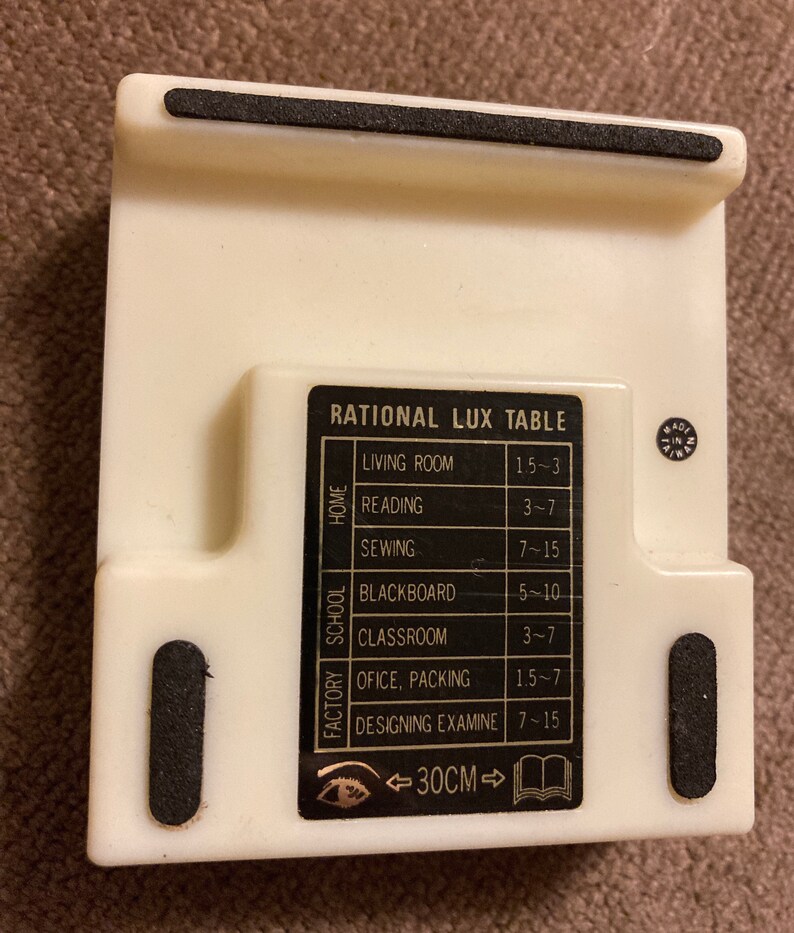 May include: A cream-colored plastic table stand with a black label that reads "RATIONAL LUX TABLE." The stand has a built-in measurement of 30 cm. It features a list of activities with corresponding measurements.