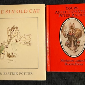 May include: Two vintage children's books. "The Sly Old Cat" features a cat illustration, and "Yours Affectionately, Peter Rabbit" has a rabbit illustration on a red cover. Both books are by Beatrix Potter.