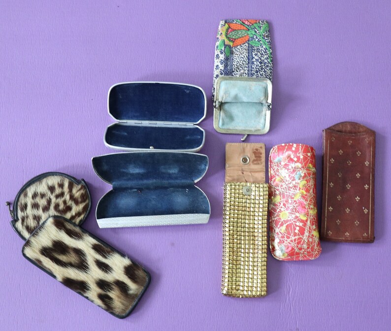 May include: Assortment of vintage eyeglass cases in various colors and patterns.  The cases are made of different materials, including leather, fabric, and metal.  Some of the cases have a floral design, while others have a geometric pattern.
