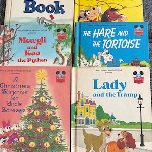 May include: A collection of vintage Disney storybooks. Titles include "Disney's Year Book", "Goofy in the Wild West", "Mowgli and Kaa the Python", "The Hare and the Tortoise", "A Christmas Surprise for Uncle Scrooge", and "Lady and the Tramp".