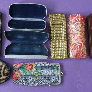 May include: Assortment of vintage eyeglass cases in various materials and patterns, including leopard print, floral, and metallic mesh.