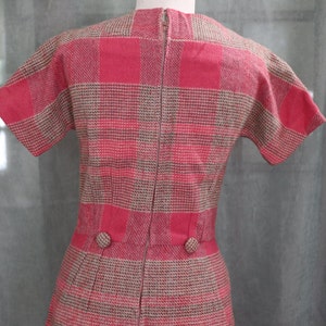 May include: A pink and brown plaid dress with short sleeves and a zipper down the back. The dress has two buttons on the waist.