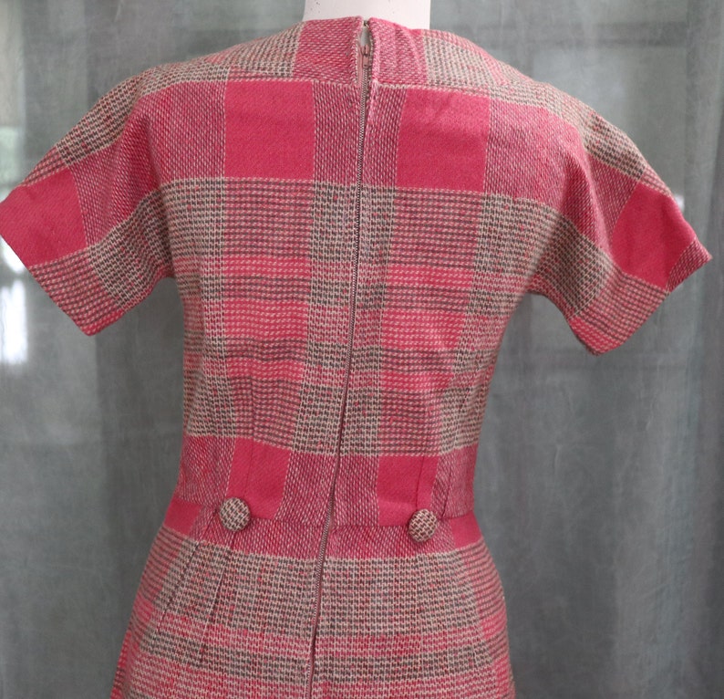 May include: A pink and brown plaid dress with short sleeves and a zipper down the back. The dress has two buttons on the waist.
