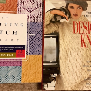 May include: Two books on knitting. The book on the left is titled "The New Knitting Stitch Library" and features various stitch patterns. The book on the right is "Vogue Knitting Designer Knits" with a woman wearing a cable knit sweater.