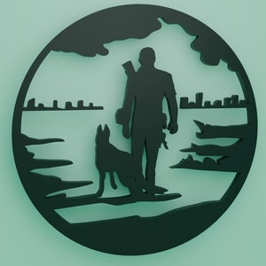 Puede incluir: Silueta negra de una persona con un perro de pie en una playa con una ciudad en el fondo. La silueta está recortada de una pieza redonda de madera.