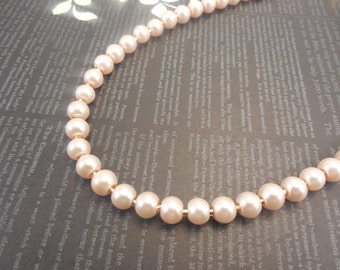May include: A delicate necklace made of pale pink pearls strung on a gold chain. The pearls are round and smooth, and the necklace is a classic and elegant design.