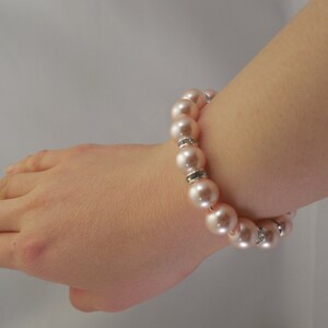 May include: A pink pearl bracelet with silver accents. The bracelet is made of round pearls and has a simple design.