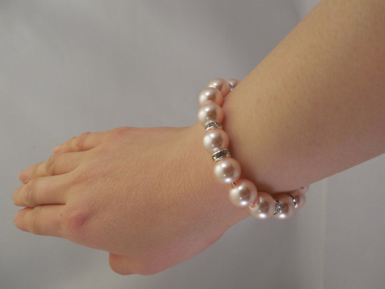 May include: A pink pearl bracelet with silver accents. The bracelet is made of round pearls and has a simple design.