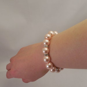 May include: A bracelet made of light pink faux pearls with silver accents.