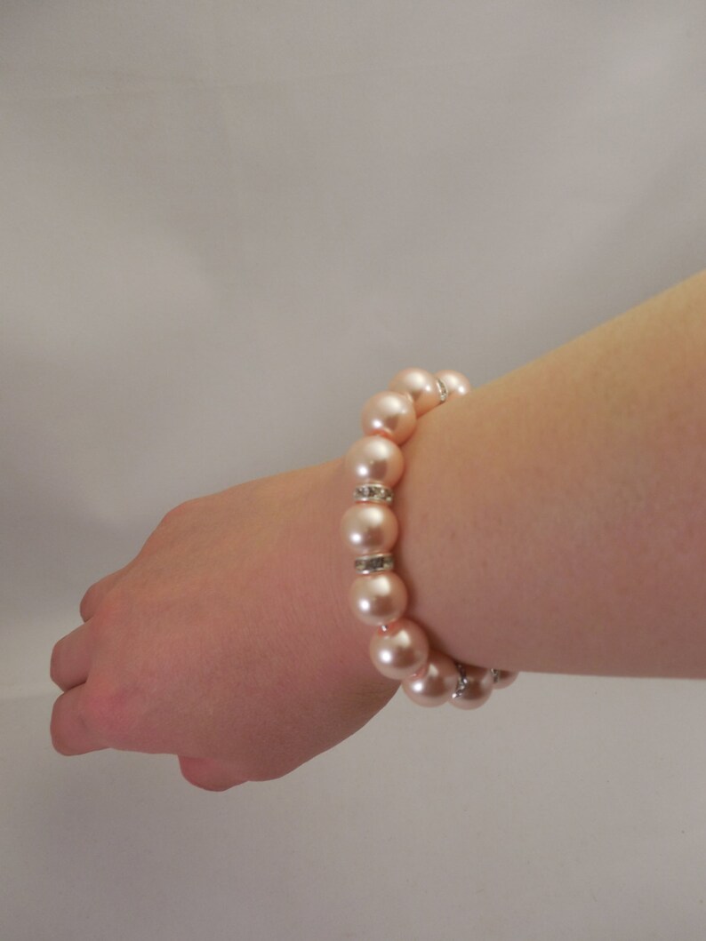 May include: A bracelet made of light pink faux pearls with silver accents.