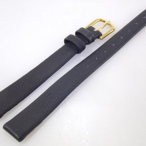 May include: A black leather watch strap with a gold buckle.