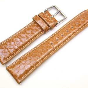 May include: A light brown leather watch strap with a silver buckle. The strap has a textured pattern that resembles snakeskin.