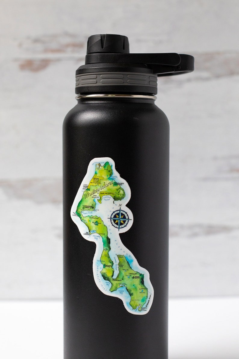 May include: Black insulated water bottle featuring a sticker of a map of Whidbey Island, Washington. The map depicts the island's coastline, key towns, and a compass rose.