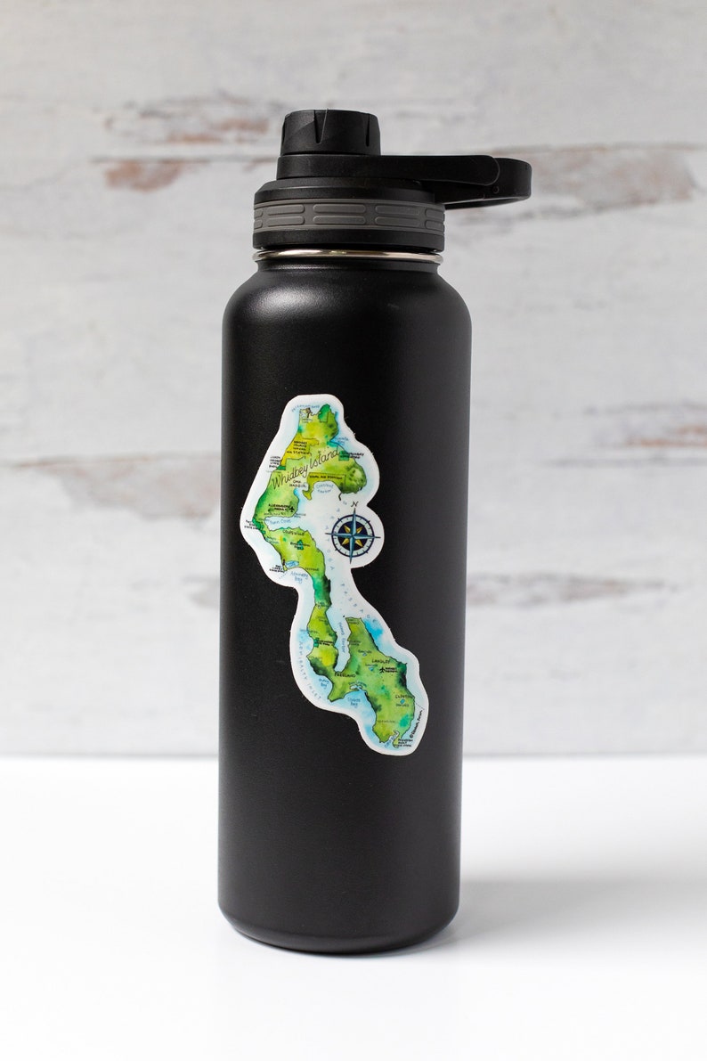 May include: Black insulated water bottle with a sticker of a map of Whidbey Island, Washington. The sticker shows the island's coastline, major towns, and a compass rose.