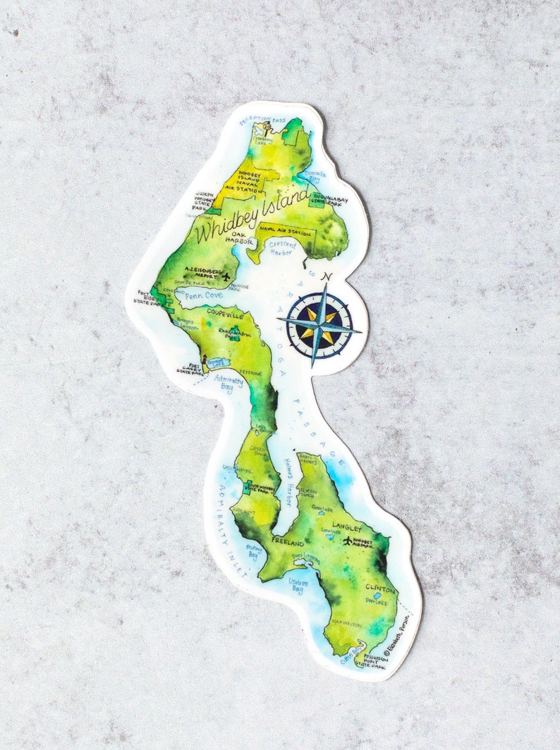 May include: A watercolour illustration of Whidbey Island, Washington, with a compass rose and key locations labelled. The island is depicted in shades of green, blue, and brown, with the water surrounding it in shades of blue.