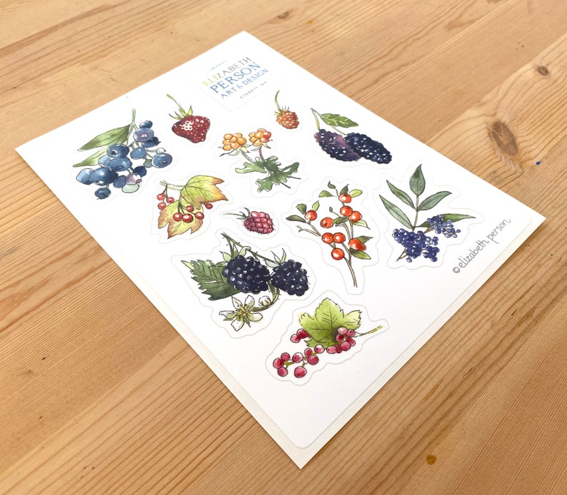May include: A sheet of stickers featuring watercolor illustrations of various berries, including blackberries, blueberries, raspberries, and red currants. The stickers are on a white background and have a handwritten signature at the bottom.
