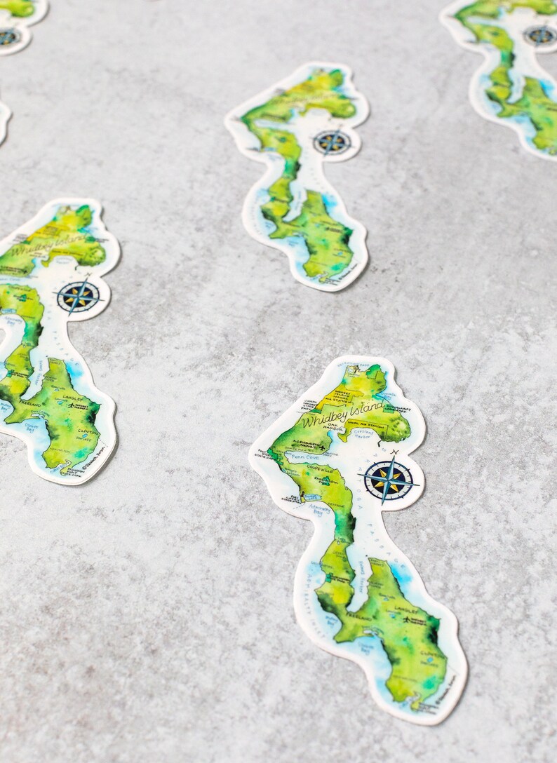 May include: Four watercolour-style maps of Whidbey Island, Washington State. Each map is printed on white paper and features a compass rose, island details, and the text "Whidbey Island".