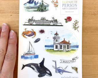 May include: A sheet of stickers featuring watercolour illustrations of various landmarks and nature scenes from Mukilteo, Washington. The stickers include a ferry, a lighthouse, a sailboat, an orca whale, a mountain, a crab, a sea urchin, a red rose, a pine tree, and a paper crane. The stickers are designed by Elizabeth Person Art & Design.