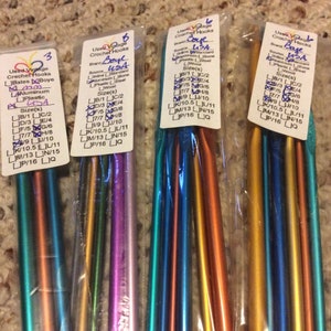 May include: Four packages of crochet hooks, each containing a variety of sizes. The packages are labeled with the brand "Boye" and the sizes of the hooks. The hooks are made of different materials, including aluminum, plastic, and steel.