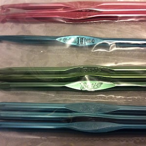 May include: A set of six crochet hooks in a clear plastic bag. The hooks are in three colors: red, green, and blue. The hooks are labeled with their sizes: US H/8, US I/9, and US J/10.