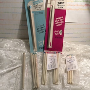 May include: A set of six vintage crochet hooks in various sizes, packaged in plastic bags. The hooks are made of white bone and have blue, pink, and green coloured tips. The packaging includes labels with the text "Luxite Bone Crochet Hook" and "Bone Crochet Hook".