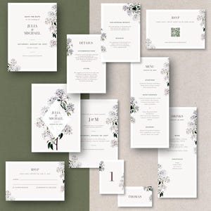 Könnte beinhalten: Eine Sammlung von Hochzeitspapeterie mit floralem Design. Das Set umfasst Einladungen, RSVP-Karten, Menükarten und Tischkarten. Der Text enthält die Namen "Julia & Michael" und das Datum "28. August 2027". Das Design zeigt weiße Blumen und grüne Akzente.