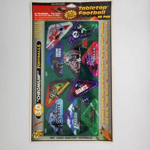 May include: A Tabletop Football 30 Pak collector series set in original packaging. The package contains ten triangular-shaped footballs featuring various NFL team logos and names, including Patriots, Colts, Dolphins, Bills, Redskins, Giants, Cowboys, Eagles, and Cardinals.