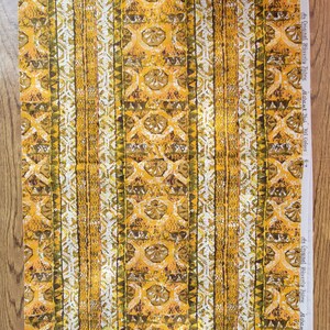 May include: A length of fabric featuring a vertical striped pattern in shades of mustard yellow, olive green, and white. The design includes repeating geometric shapes and floral motifs. The selvage edge displays the text An Original Waverly Fabric.