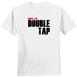May include: White t-shirt with black text that reads "RULE #2 DOUBLE TAP". The number 2 is in red.
