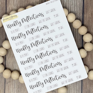 May include: A sheet of white sticker paper with black text. The text reads "Weekly Reflections" and includes the phrases "Adjustments", "Lessons Learned", "What's Working", "What Isn't Working", and "My Wins".