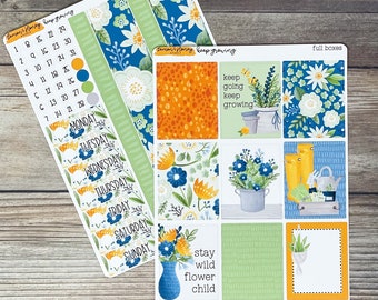 May include: A set of planner stickers with a floral theme. The stickers include a calendar, days of the week, full boxes, and decorative elements. The stickers are in shades of blue, green, yellow, and white.