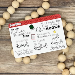 Könnte beinhalten: Eine rot-weiße Weihnachtskarte mit dem Text "In my Holiday Romance Era 'Tis the season to Read Dear Santa, Bring Books" und "All I want for Christmas is Books Season's Readings My Holidays are all Booked up Have your shelf a Bookish Little Christmas".