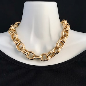 May include: A thick gold chain necklace with large oval links.