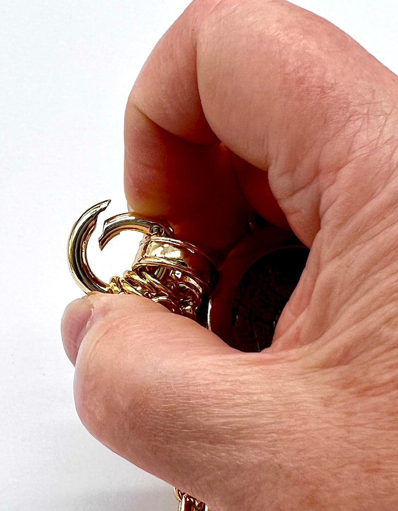 May include: Gold-toned chain with a lobster clasp. The chain is made of multiple linked rings.