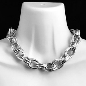 May include: A silver chain necklace with large, oval-shaped links. The links are interlocked and have a polished finish.