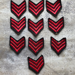 May include: Twelve red and black chevron patches. The patches are made of fabric and have a velvet-like texture.