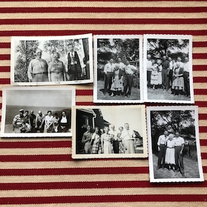 May include: A collection of black and white vintage photographs of families and groups of people. The photos are arranged in a grid pattern on a red and white striped surface.