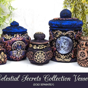 May include: A collection of four decorative ceramic jars with intricate designs. The jars are painted in shades of blue, purple, gold, and copper. Each jar features a different celestial motif, including a moon, sun, and stars. The jars are labeled "Celestial Secrets Collection Vessels (SOLD SEPARATELY)".