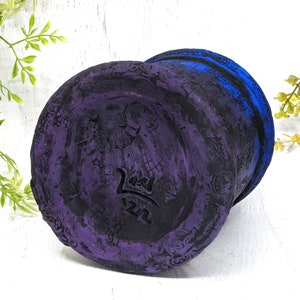 May include: A purple and blue ceramic planter with a decorative design and the text "22" on the bottom.