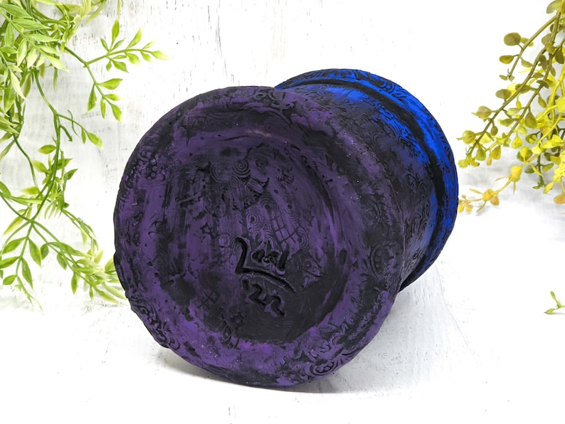 May include: A purple and blue ceramic planter with a decorative design and the text "22" on the bottom.