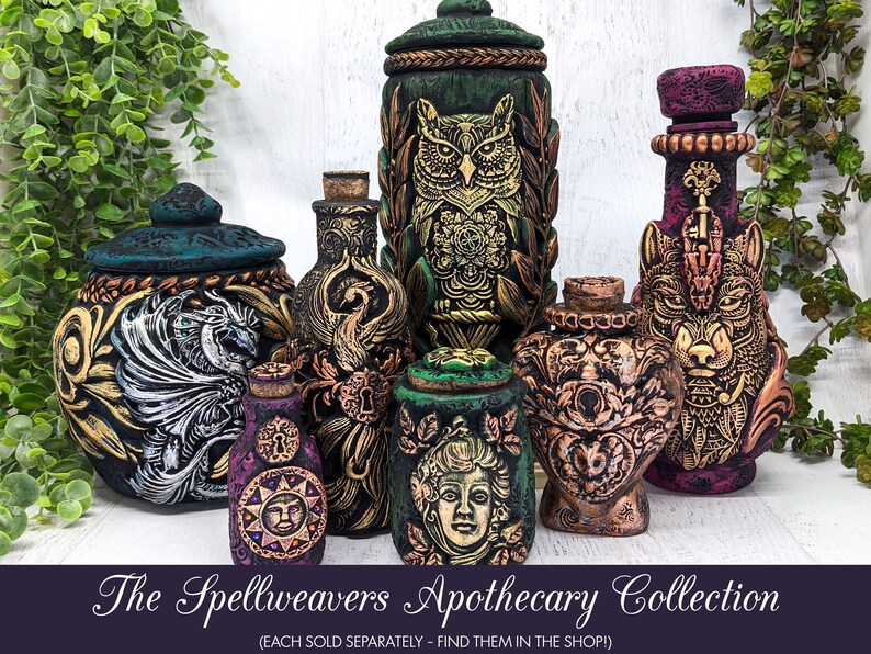 May include: A collection of seven decorative ceramic jars with lids, each featuring a different mythical creature or design. The jars are painted in shades of green, black, gold, and purple, and have intricate details. The jars are labeled "The Spellweavers Apothecary Collection".