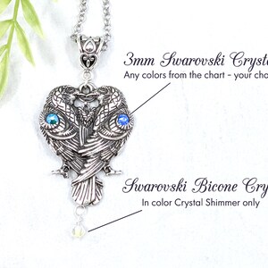May include: Silver pendant necklace featuring two stylized owls with 3mm Swarovski crystals for eyes. The pendant is attached to a silver chain and has a single Swarovski bicone crystal hanging from the bottom.