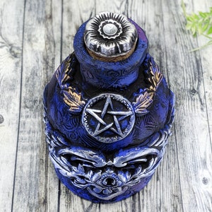 May include: A blue ceramic bottle with a silver pentagram design and a silver flower-shaped stopper. The bottle has gold leaf accents and intricate details.