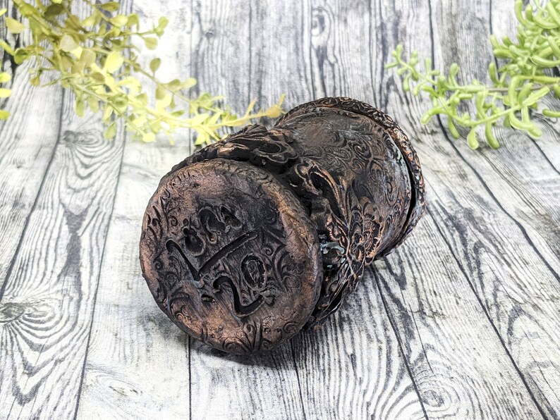 May include: A dark brown ceramic planter with intricate floral designs and the word "Luck" embossed on the bottom.