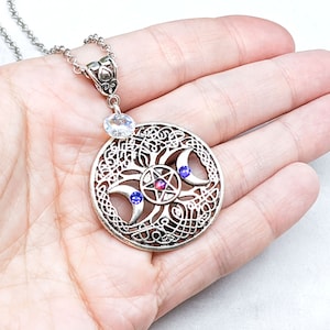 May include: Silver necklace with a circular pendant featuring a triple moon symbol, a pentagram, and three crystals. The pendant is surrounded by a Celtic knot design.