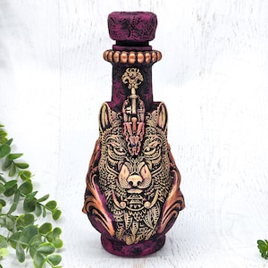 May include: A dark purple ceramic bottle with a gold wolf design. The bottle has a decorative stopper and intricate details.