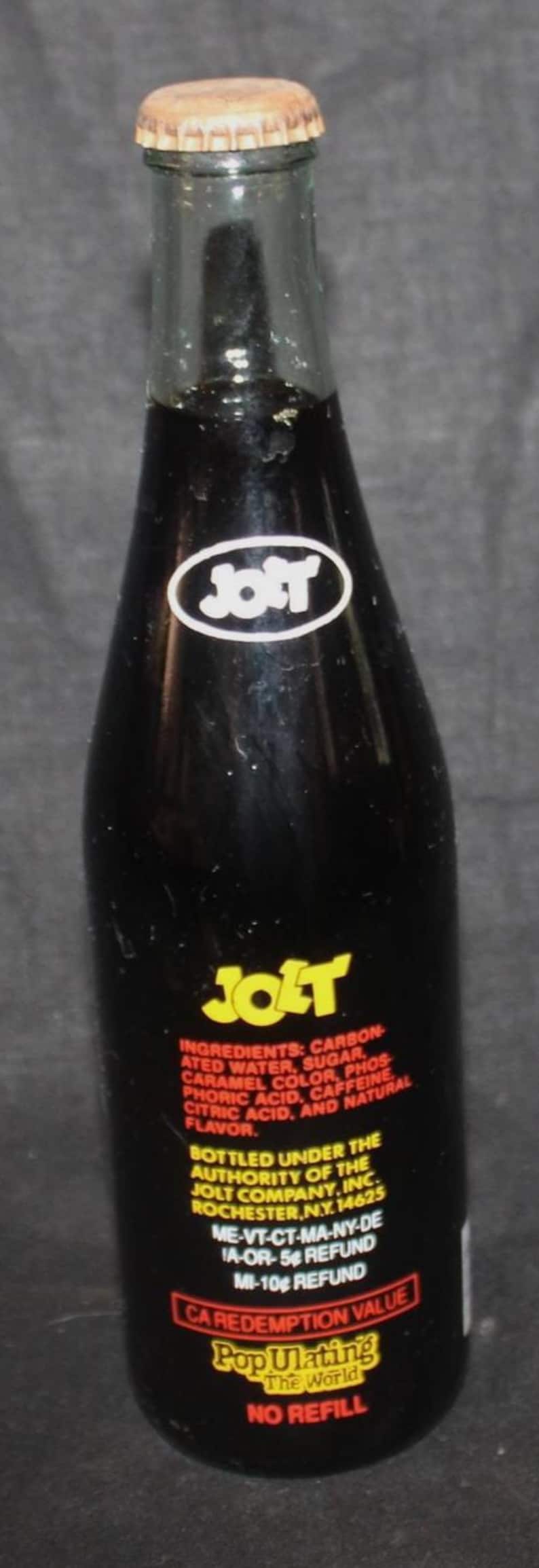 May include: A vintage Jolt Cola bottle with a brown cap. The dark glass bottle features the Jolt logo and text detailing ingredients and redemption value. The label reads "Populating The World."