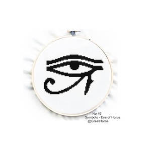 以下が含まれることがあります： 丸い刺繍枠の中に、ホルスの目のシンボルが黒と白のクロスステッチで刺繍されています。下のテキストには「No. 46 Symbols - Eye of Horus @GreatHome」と書いてあります。